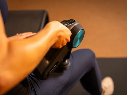 A member using a massage gun to perform Percussion Stretch Therapy
